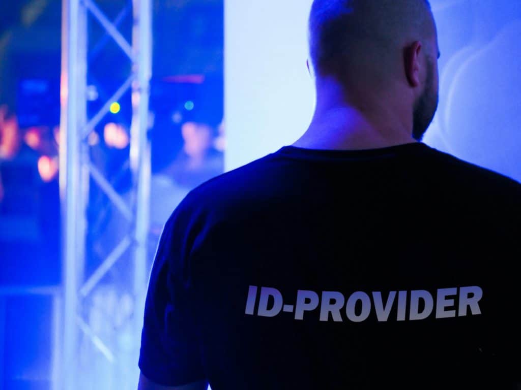 Ein Türsteher steht vor einem Club und statt "Security" steht "ID-Provider" auf seinem T-Shirt